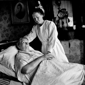 823236 Afbeelding van een Zuster Augustinesse aan het ziekbed van een bewoonster, waarschijnlijk uit Wijk C te Utrecht.